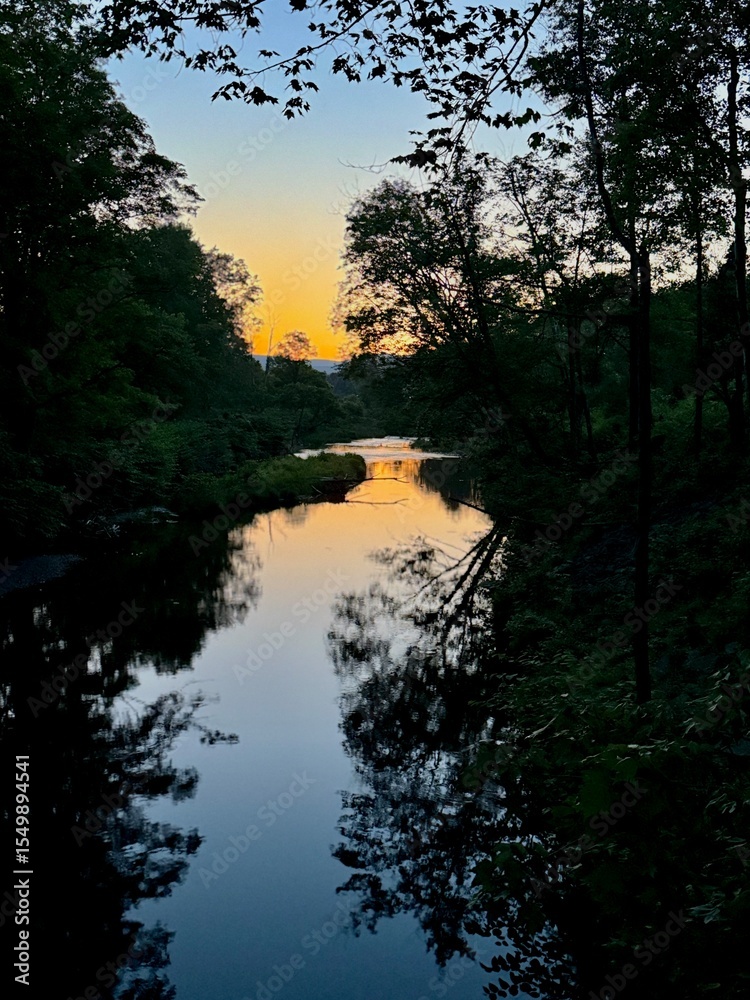 Obraz premium Summer vibes. Night at sunset. blue orange sky which reflects in the waters of Windham Path in Catskill Mountains ski town. Mountain peaks in the distance. Clear sky at dusk. Quiet and serene beauty
