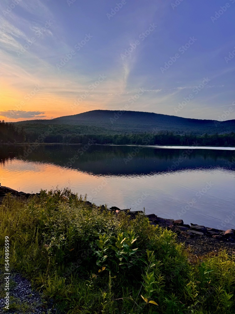 Obraz premium Breathtaking mountain peak at sunset. Stunning scenic view. North South Lake Campground in the Catskill Mountains. Serene summer, dusk. Clear calm blue orange purple sky clouds reflect over lake.