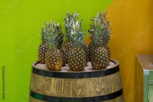 Fresh pineapples displayed on a wooden barrel in a vibrant setting