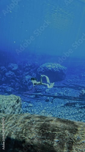 Woman freediver underwater in Paisu Pok lake. Transparent blue lake and beautiful woman in Indonesia
