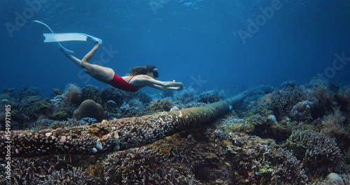 Amazing corals and pretty woman freediver underwater in blue sea, freediving in Raja Ampat