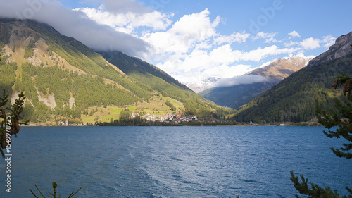View over Lake Reschen to the village of Curon Venosta in front of the mountains.