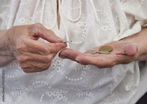 The wrinkled hands of an old woman count coins