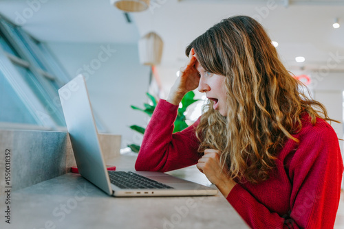 Professional woman showing shock while viewing laptop screen during video call, experiencing unexpected workplace communication in contemporary office environment