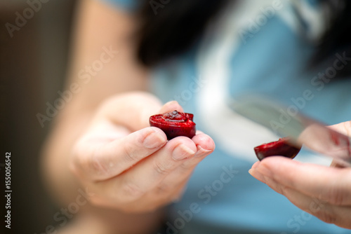 Woman's hands cutting ripe cherries to prepare a delicious homemade meal or dessert