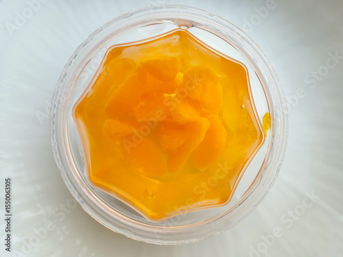 Mandarin orange slices in jelly on a plate on a white table.