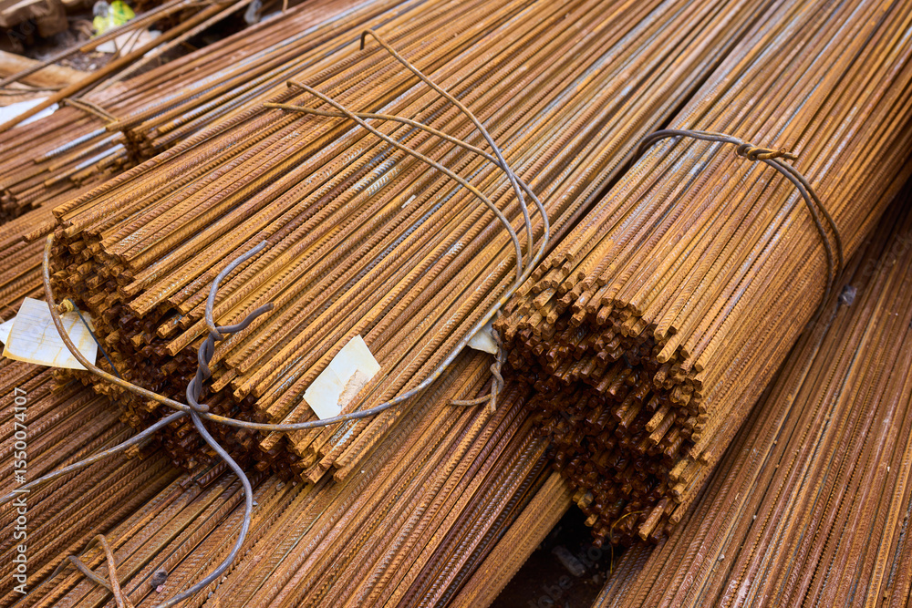 Obraz premium Stacked steel rods are prominently observed at a bustling construction site in progress