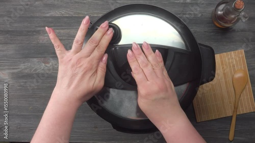 Hand closing lid of instant pot pressure cooker where beef chili and beans are being stewed, top view. High quality 4k footage