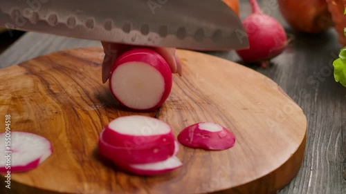 A closeup or macro shot of a sharp kitchen knife carefully slicing a fresh red radish into thin rings. Preparing healthy salad ingredients for a delicious and nutritious meal. High quality 4k footage