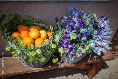 On a bench is a basket filled with lavender and oranges