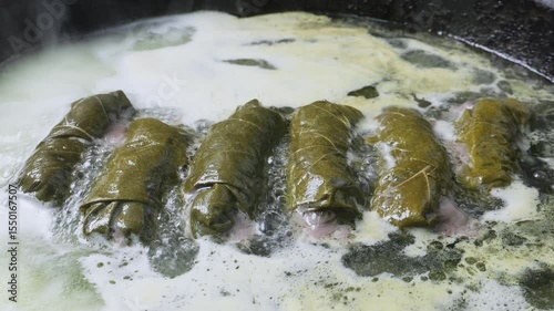 Homemade dolma with lamb is stewed in a frying pan with boiling vegetable oil and water. Medium shot.