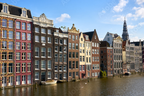 Damrak Dancing Houses in Sunshine Amsterdam Netherlands. Amsterdam's famous Damrak Dancing houses and canal reflections on a sunny day.

