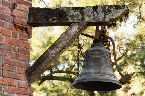 Antigua campana de hierro en soporte de madera amurada al ladrillo