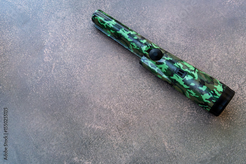 A hand-held metal pinpoint detector in protective color.A device for finding wires in the wall.