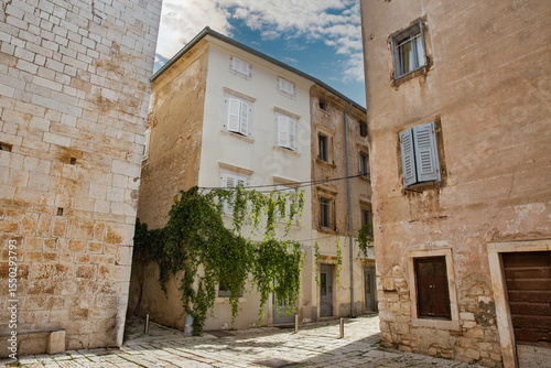 Picturesque narrow street with green plants in Porec, Croatia.