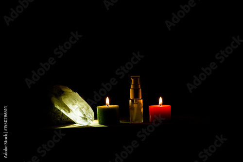 Ritual espiritual con velas encendidas, cristal de cuarzo y frasco de esencia sobre fondo oscuro