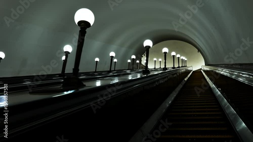 Long escalator going up in metro station with many lights illuminating the path