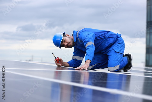 Solar engineer or Industrial technician with mechanic suit working check quality of solar panel on solar roof, green and reusable energy concept 