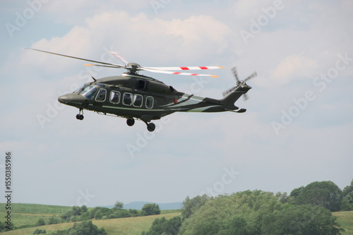 military transport helicopter with its landing gear down hovered over the ground as it approaches for landing