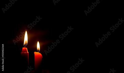 Dos velas rojas encendidas en fondo negro, iluminación tenue y concepto de espiritualidad o reflexión