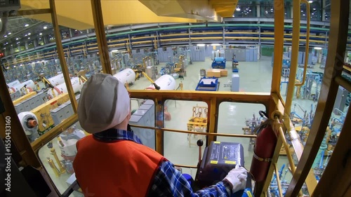 Industrial chemical Production. Inside of the Crane Operating Room. Worker Wearing an Orange vest is Moving the Crane by turning the handle of the lever. Using the Crane at the Factory. Slow motion