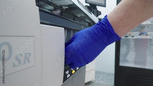 Patients Biomaterial Samples Inserted Into Medical Examination Machine. Scientist Loads Samples Into Machine For Medical Examination. Medical Examination Of Samples By Machine For Diagnosis