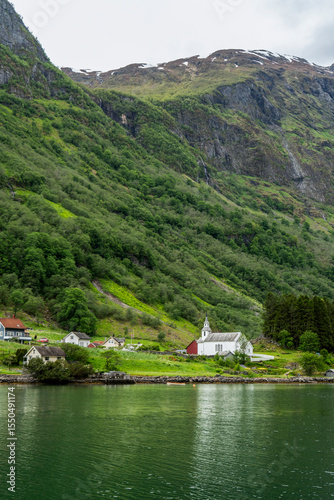 Idyllic village and church on a green fjord shore