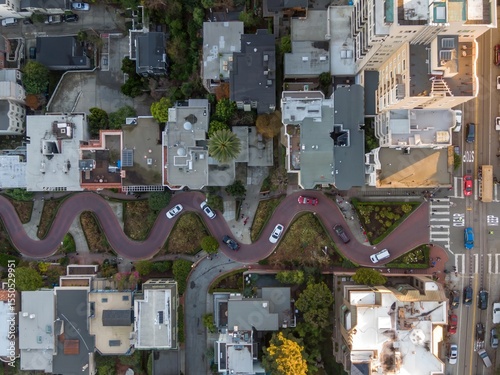 Aerial view of cars driving down Lombard Street, known for its steep, one-block section with eight hairpin turns, in San Francisco, USA. Tourists walk.