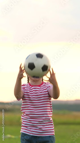 Laughing little girl playing football ball at summer sunset field enjoy happy childhood. Smiling cute female kid child tossing soccer sport equipment have fun outdoor leisure activity positive emotion