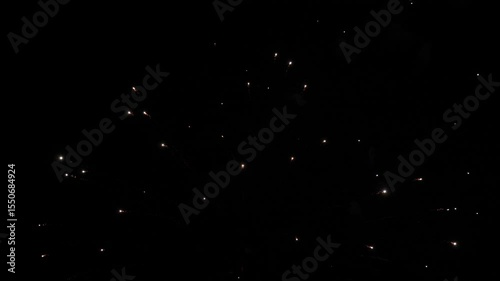 Firework explosions with glowing traces and stars in sky at nighttime holiday. Brilliant display of firework flashes illuminate black sky. Firework performance for spectators at evening party