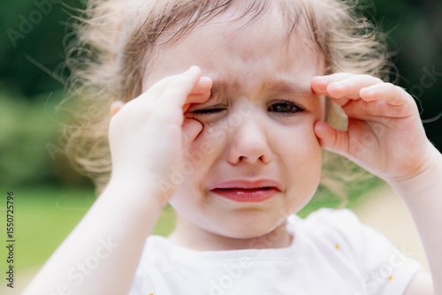 Beautiful little cute girl crying in the park.