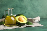 Jug of avocado oil on green background