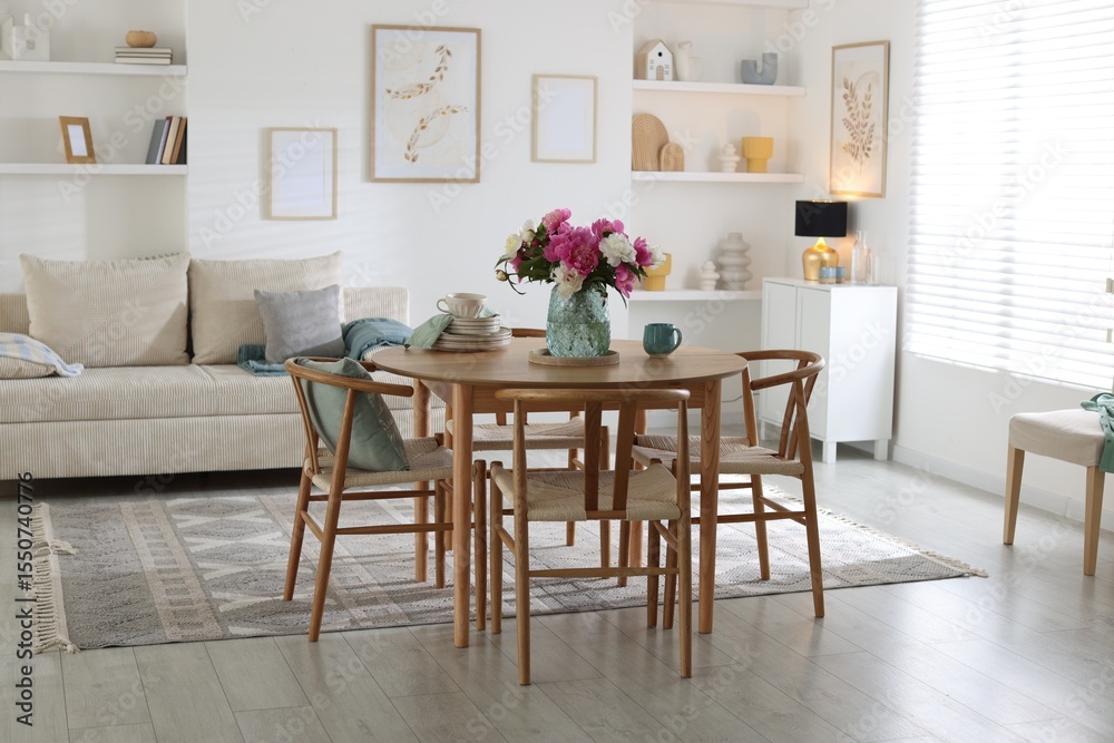 Dining table with beautiful flowers and dishware in room. Interior design Dining table with beautiful flowers and dishware in room. Interior design