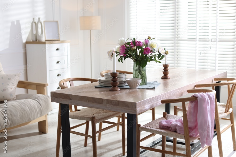 Fototapeta premium Dining table with beautiful flowers and dishware in room. Interior design