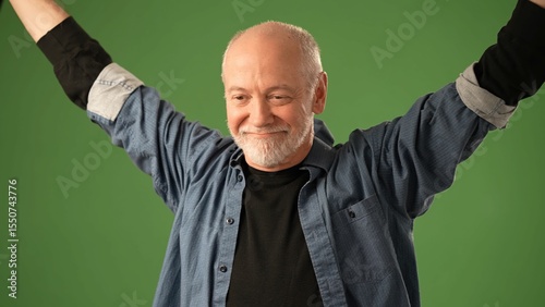 A senior man stands in front of a solid green background, showcasing various emotions with open hands and an expressive face, engaging the viewer directly.