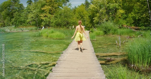 Wallpaper Mural Woman crossing wooden path over clear lake in Plitvice in summer Torontodigital.ca