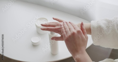 Beautiful woman applying cream on hand skin, slow motion. Female hands care. beautiful lady applying hand cream at home. White cream rubbing to treatment skin condition. Hygiene and skin care concept.