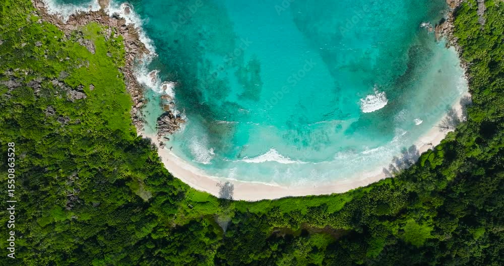 Tropical beach with clear turquoise water and vibrant green vegetation surrounding it. Seychelles, La Digue.