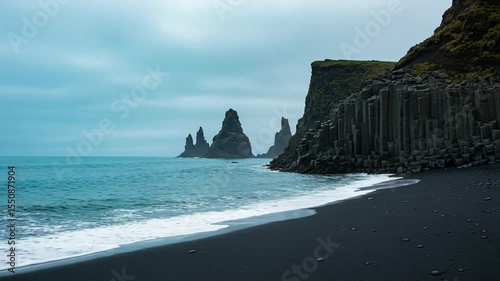Rugged coastline with basalt columns and sea stacks under cloudy sky