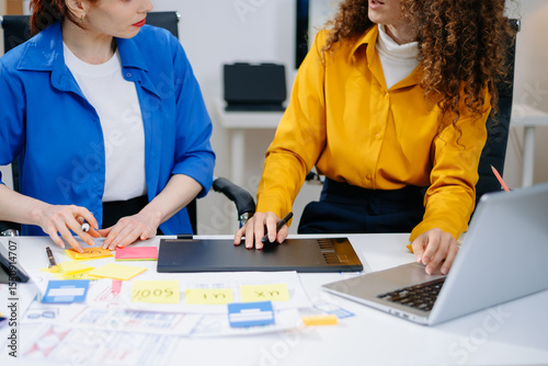Closeup of UX UI designers planning mobile layouts with wireframes, color swatches, sticky notes, and smartphones.