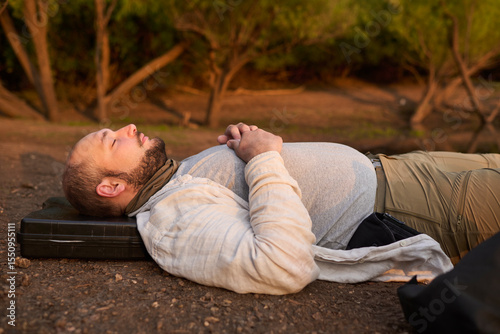 Man lying on the ground early in the morning, receiving the first rays of the sun with a relaxed and calm expression. El Palmar National Park, Entre Rios, Argentina.