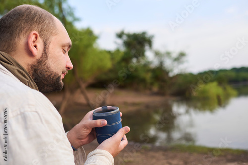 Hispanic man enjoys a cup of freshly brewed coffee in nature, early in the morning. His expression is one of tranquility, calm and well-being. El Palmar National Park, Entre Rios, Argentina.