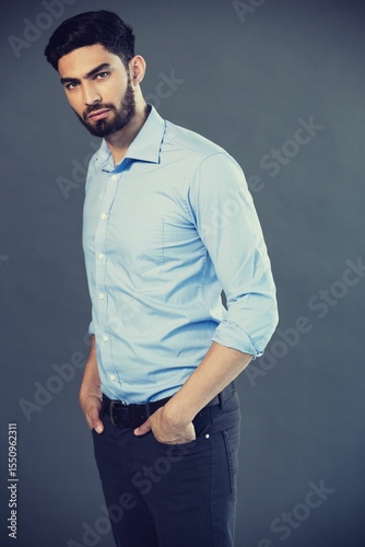 Portrait of young man standing against gray background