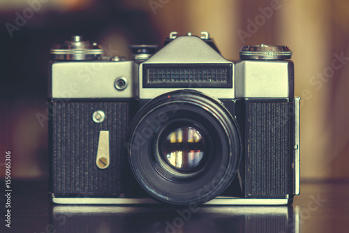 An old film camera with a metal body. The photo is made in a retro style with soft focus and a warm color palette.