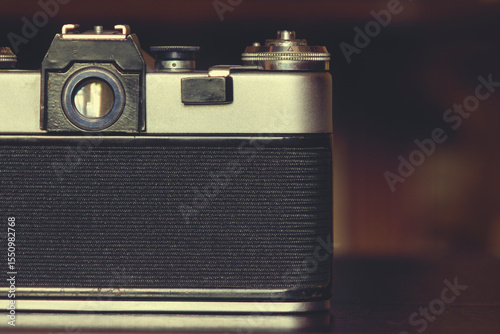 The back of a vintage analog camera. Part of the camera body is visible with controls, including a viewfinder and a control dial, a retro design typical of older models of photographic equipment.