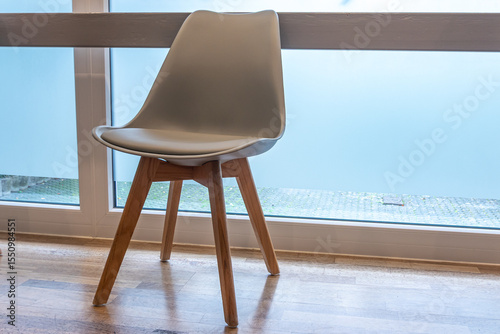 Modern gray chair in waiting room by window with parquet floor