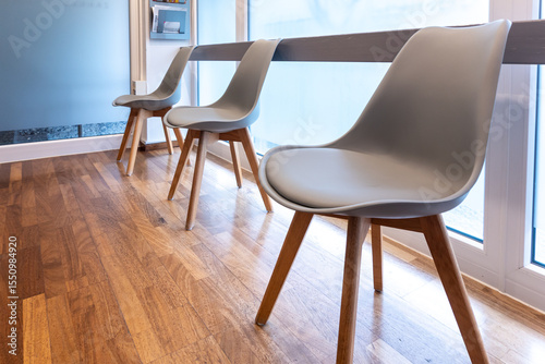 Modern gray chairs in waiting room by window with parquet floor