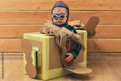 Kid play with imagined wings. Imaginative child dreams of flying. Cardboard wings spark imagination play. Creative kid play pilot. Kids play with imagination. Children playing with toy plane at home.