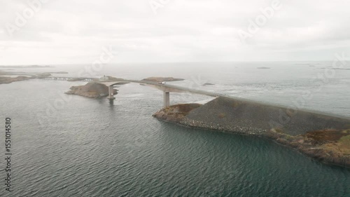 Atlantic ocean road with Storseisundet bridge forming distinctive arc over water connecting landmasses. Rugged beauty of Norway engineering marvel