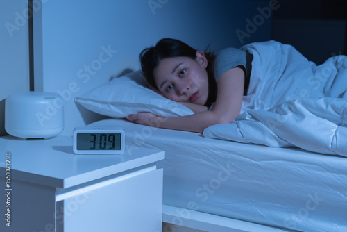 Fotografie Annoyed, stressed, anxiety asian young woman suffering from insomnia, frustrated awake on bed at night, headache or migraine, health care problem, disturbed trouble of loud noise, unable sleepless